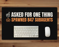 Black 24 x 14 inch desk mat that reads "Asked for one thing / Spawned 847 subagents", on a wood desk with a keyboard and mouse below the joke